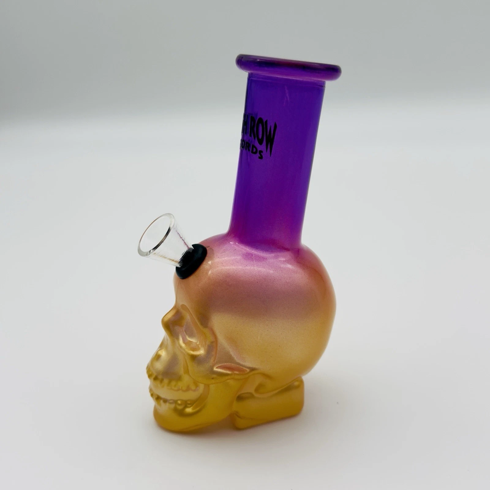 Glass skull-shaped pipe with purple top on a white background
